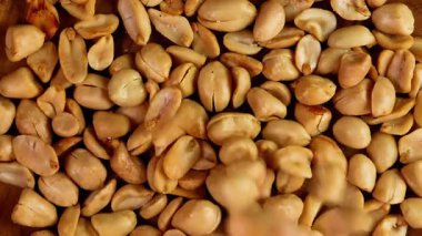 Kabuklu tuzlu fıstıkların siyah arka planda ahşap bir tabağa düşüşünün yavaş çekimi. Reklam ya da tanıtım için uygun.