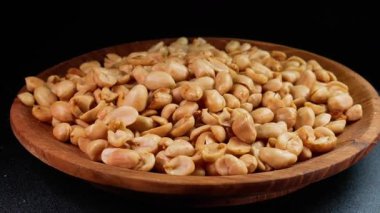 Derisi olmayan kızarmış fıstık, pikapta siyah arka planda servis edilen ahşap bir tabakta. Reklam ya da tanıtım için uygun.