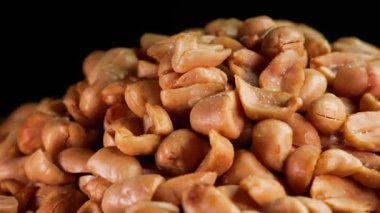 Koyu bir arka planda dönen kabuklu, kavrulmuş fıstık yığınının yakın çekimi. Reklam ya da tanıtım için uygun. Yatay çekim