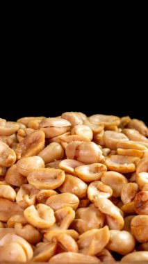 Siyah arkaplanlı tuzlanmış fıstık yığını yakın plan. Atıştırmalık, bayram veya aşçılık konsepti teması için mükemmel..
