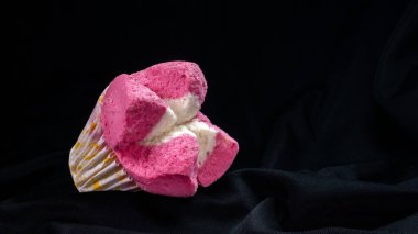 Siyah kumaşlı yumuşak desenli pembe buharlı sünger kek. Dramatik ışık, reklam veya promosyon için uygun..