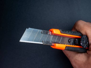 Turuncu-siyah saplı ve keskin bıçaklı metal alet bıçağı, ofis veya iş aletleri için idealdir..