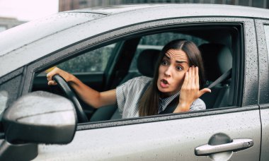 Trafik sıkışık. Saldırgan sürücü. Araba kazası. Kapalı portre, kızgın bir kadının araba kullanmasından ve yumruğu havada birine bağırmasından rahatsız oluyor. Negatif insan ifadesi