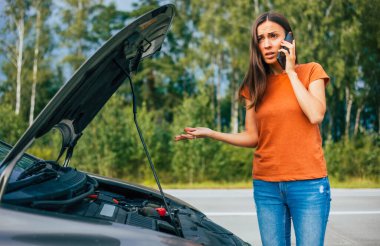 Bozuk ya da yolda bozuk bir araba. Problemli araba kullanırken genç kadın sürücünün cep telefonu kullandığı fotoğraf. Araç Sigortası, Bakım ve Servis Konsepti