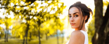 Güneş ışınlarıyla gün batımında açık havada poz veren güzel ve güzel esmer bir kadının portresi. Moda, tarz, moda, model