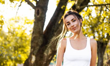 Güneş ışınlarıyla gün batımında açık havada poz veren güzel ve güzel esmer bir kadının portresi. Moda, tarz, moda, model