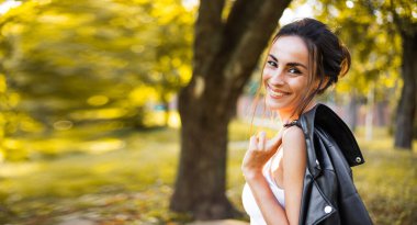 Güneş ışınlarıyla gün batımında açık havada poz veren güzel ve güzel esmer bir kadının portresi. Moda, tarz, moda, model