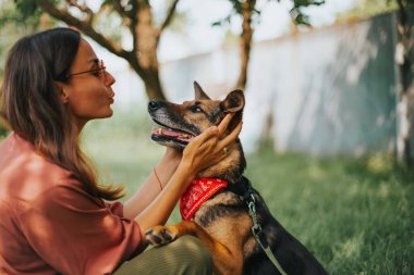 Güneş gözlüklü, gülümseyen güzel bir kadın parkta köpeğine sarılıyor. Mutlu ev sahibi ve evcil hayvanı. Barınaktan kurtarılan köpek.