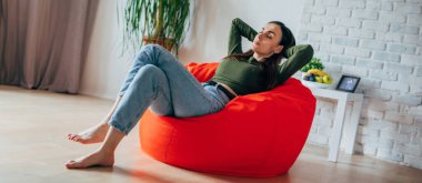 Güzel, genç, esmer bir kadın, günlük kıyafetleriyle evdeki fasulye çuvalında oturuyor ve rahatlıyor, dinleniyor, düşünüyor ve meditasyon yapıyor.