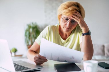 Emeklilik ve mali belgeler, evraklar, planlama, finansal banka ödemeleri, tasarruflar ve ev hesapları için dizüstü bilgisayarlı bütçe planına sahip olgun bir kadın.
