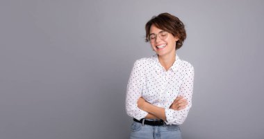 Zeki resmi gömlekli ve gözlüklü, kendine güveni tam bir çalışan şirket avukatı kadın. Ofiste çalış. Gri arka plan stüdyosunda izole edilmiş şık saç stiline sahip bir kadın..