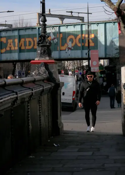 Londra, Birleşik Krallık, Ocak 12022: Camden Lock Köprüsü tamamen siyah giyinmiş şık bir adamla kameraya doğru yürüyor.