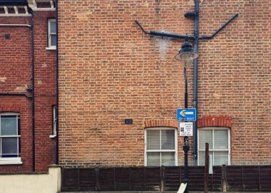 Tuğladan duvarları olan Londra evleri tek yönlü trafik işareti ve park yeri sahiplerinin tabelasını gösteriyor.