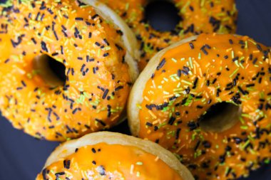 Cadılar Bayramı temalı donutlar turuncu kremalı, siyah yeşil ve beyaz serpiştirmeli, yukarıdan manzara