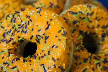 Cadılar Bayramı temalı donutlar turuncu kremalı, siyah yeşil ve beyaz serpiştirilmiş
