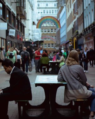 London, England, Apr 30 2023: Carnaby Street street view with people walking around and sitting in a bench clipart