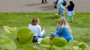 Londra, İngiltere, 10 Mayıs 2023: İki bayan Kensington Sarayı 'nda oturmuş piknik yapıyor ve güneşli bir günün tadını çıkarıyor.