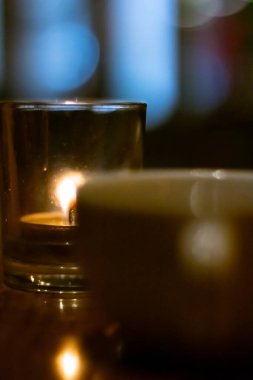 Bulanık camlı ve arka planlı bir restoran masasında yanan mum.