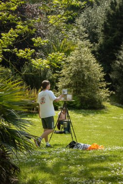 Londra, İngiltere, 24 Mayıs 2023: Güneşli bir günde Battersea Parkı 'ndaki tuvalde resim yapan adam