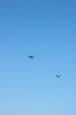 Londra üzerinde mavi gökyüzünde uçan iki helikopter.