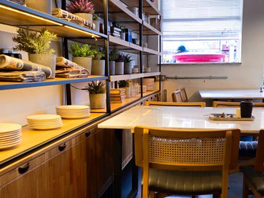 Kafe manzaralı boş masalar, birinin kirli tabakları ve sokak manzarası var.