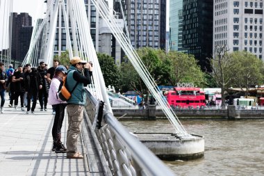 Londra Gözü 'nün Thames nehri üzerindeki bir köprüde fotoğraflarını çeken turistler..