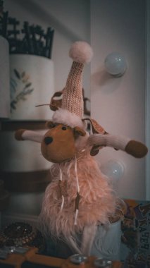 Yumuşak, şenlikli bir ren geyiği, örgü bir şapka ve eşarp giyip tatil atmosferine sıcaklık ve cazibe katıyor. Noel temalı dekorasyon ve rahat kış ayarları için mükemmel..