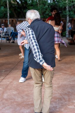 Yaşlı bir çift açık hava halk etkinliğinde dans ediyor..