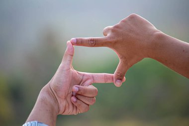 Kişinin elleri doğada çerçeve uzaklığı veya sembol oluşturur.