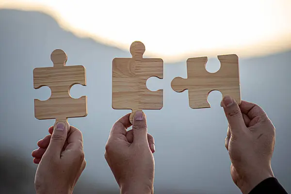İş başarısı ve strateji çözümleri kavramı, Eller kadın güneş ışığı arka planına sahip çift bulmaca parçalarını birbirine bağlar