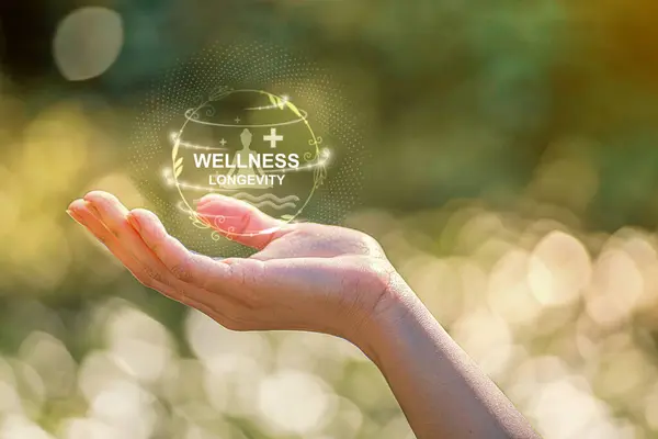 Refah ve uzun yaşam kavramı. Bir el, sağlık, doğa ve uzun vadeli refahın entegrasyonunu sembolize eden, refahın ve uzun ömürlülüğün dijital bir temsilini tutar..