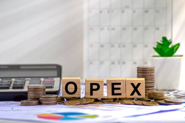 OPEX kelime ahşap küpler üzerinde, küpler yansıtıcı bir yüzey üzerinde duruyor, arka planda bir iş diyagramı var. İş ve finans kavramı