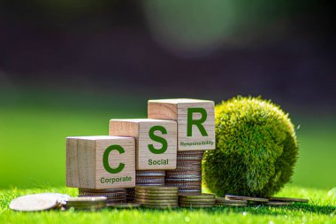 CSR (sosyal sorumluluk eşgüdümü). Tahta blokta CSR ve yeşil arka planda yeşil dünya. Bu kurumsal sosyal sorumluluk ve toplumsal aktivite kavramı için bir fikir..
