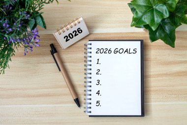 2026 Yeni Yıl hedefi, planı ve eylem kavramları. 2026 gol Not Defterine Takvimle Metin, Masada Gözlükler. Yeni Yıl Kararları Planı. Mutlu yıllar teması, üst görünüm