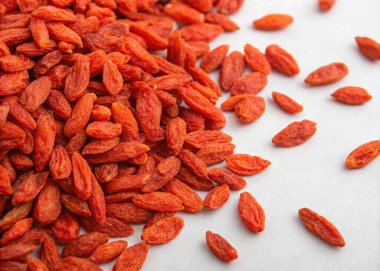 A close-up photograph featuring a pile of dried red goji berries, with a rich, vibrant orange-red hue. The berries are scattered in a visually appealing manner, with some appearing slightly more concentrated in the center of the pile and others scatt clipart