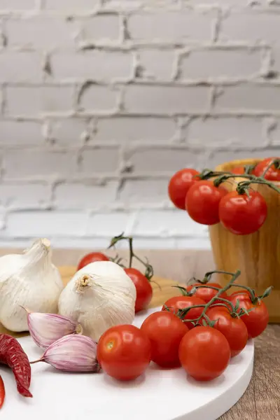 Yemek malzemeleri, sarımsaklı kırmızı kiraz domatesleri ve mutfaktaki ahşap ve mermer tahtada kırmızı biberler.