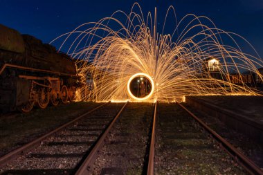 Op een verlaten station met aan de linkerzijde een oude trein fotografeerde ik deze mooie setting van vuur en licht. Staalwolfotografie is tijdens de avonduren soms pure kunst en het spoor brengt je ogen naar het spektakel clipart