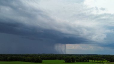 Uzakta, yaz mevsiminde kara bulutlardan yağan yağmur, insansız hava aracı çekimi.