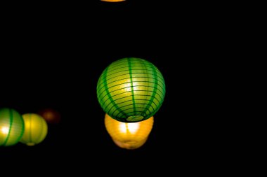 Japon dekoratif lambaları koyu siyah arka planda yuvarlak ve renklidir..