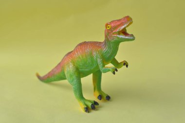 Çocuk oyuncağı dinozor sarı arka planda izole edilmiş.