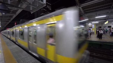Tokyo, Japonya - Ağustos 2018: Japonlar platformda sırada beklerken yerel banliyö treni metro istasyonundan ayrılıyor. Tokyo demiryolu taşımacılığı dakikliği ve kolaylığıyla tanınıyor.
