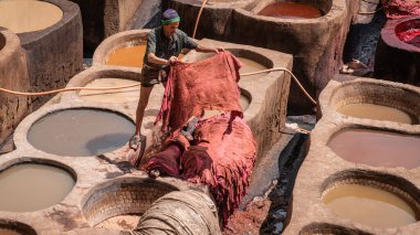 Fez, Fas - 10 Eylül 2022: Geleneksel bir tabakhanede deri ölüyor. Deri tabakhanelerdeki boya kaplarında tabakçı olarak çalışan adamlar. Bronzlaşma çukurları deri boyalarla doludur.