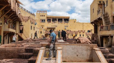 Fez, Fas - 10 Eylül 2022: Geleneksel bir tabakhanede deri ölüyor. Deri tabakhanelerdeki boya kaplarında tabakçı olarak çalışan adamlar. Bronzlaşma çukurları deri boyalarla doludur.