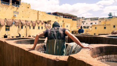 Fez, Fas - 10 Eylül 2022: Geleneksel bir tabakhanede deri ölüyor. Deri tabakhanelerdeki boya kaplarında tabakçı olarak çalışan adamlar. Bronzlaşma çukurları deri boyalarla doludur.