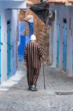 Chefchaouen, Fas - 11 Eylül 2022: Mavi şehir olarak bilinen Chefchaouen 'de yürüyen yaşlı adam, çarpıcı mavi renkli binaları ve caddeleriyle ünlü