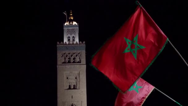 モロッコ マラケシュ モロッコの夜にモロッコの国旗を持つクトゥービア モスク ミナレット — ストック動画