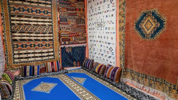 Room full of Moroccan carpets. A Moroccan carpet is a handwoven masterpiece, crafted by skilled artisans. These rugs feature geometric patterns and vibrant colors, showcasing rich Moroccan culture.