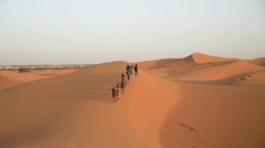 Sahra Çölü, Fas - 13 Eylül 2022: İki Berber bir deve kervanı ile kum tepelerini aştı