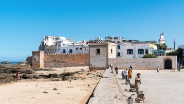 Essaouira, Fas - 17 Eylül 2022: Essaouira şehir kalesi ve Atlantik Okyanusu 'na bakan Essaouira şehir limanı yakınlarındaki Fas halkı ve turistler