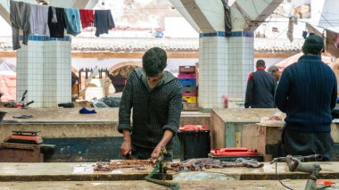 Essaouira, Fas - 17 Eylül 2022: Faslı balıkçı ustalıkla temizledi ve Essaouira balık pazarında satmak için bir ahtapot hazırladı